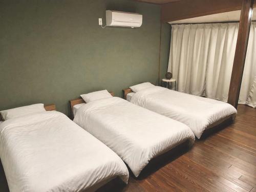 three beds in a room with white sheets at TAKIBEst Bnb&Bar in Takibe