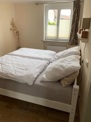a bed with white sheets and a window in a room at Modernes wohnen im alten Beelitz Wohnung 1 in Beelitz