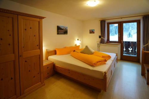 a bedroom with a bed with orange sheets and a window at Sesvennahof in Malles Venosta