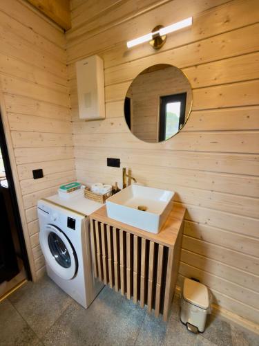 a bathroom with a sink and a washing machine at Domki Pod Stromcem in Czernica