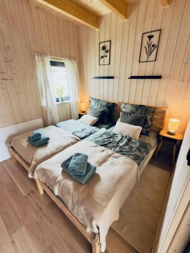 two beds in a room with wooden walls at Domki Pod Stromcem in Czernica