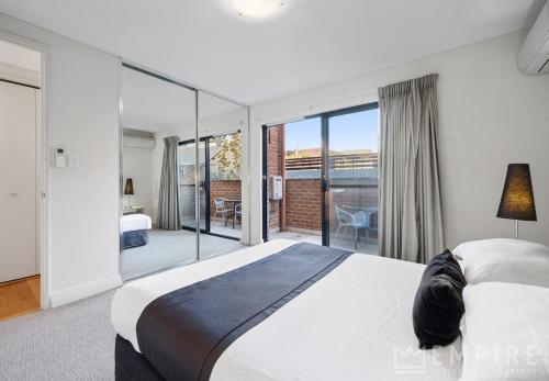 a bedroom with a large bed and a balcony at Parklane Apartments in Fremantle