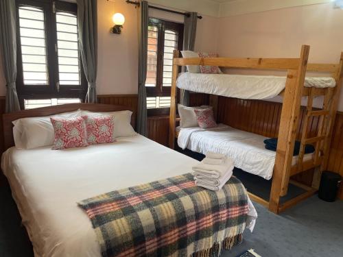 a bedroom with two beds and a bunk bed at Rato Ghar Hotel and Rooftop Restaurant in Bhaktapur