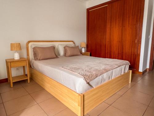 a bedroom with a bed with two night stands and two lamps at Refúgio dos Arrifes in Vila Baleira
