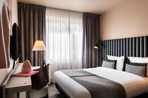 a hotel room with a large bed and a window at Hôtel Diana Dauphine in Strasbourg