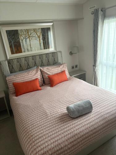 a bedroom with a large bed with orange pillows at Poppy in Ferndown