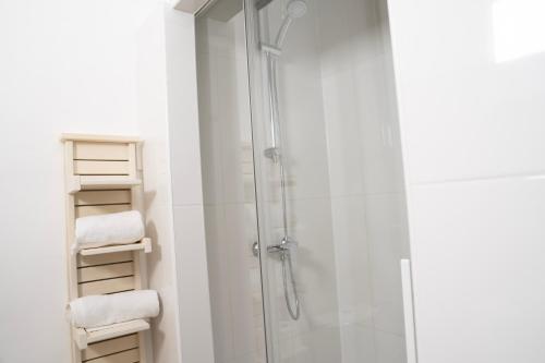a bathroom with a shower with white walls and white towels at Le National Sète Centre Gare,Ascenseur in Sète