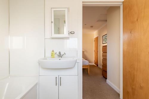a white bathroom with a sink and a mirror at West Cottage - Elie in Earlsferry