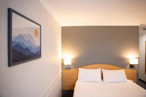a bedroom with a bed and a painting on the wall at Days Inn Hotel Leicester in Leicester