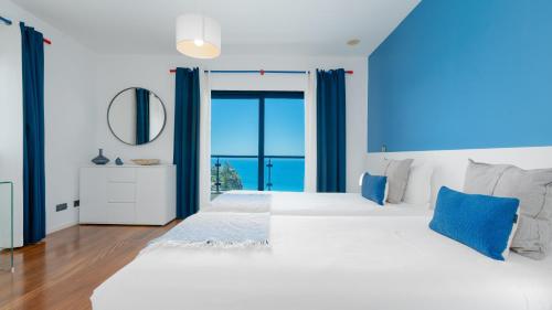 a bedroom with a large bed with blue curtains at Villa Skylark - by LovelyStay in Ponta do Sol