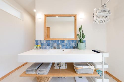 a bathroom with a white sink and a mirror at タイガーMiyako in Miyako-jima