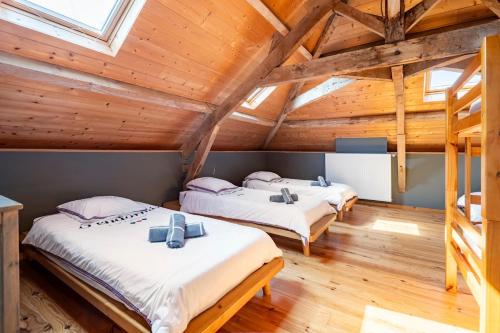 two beds in a room with wooden ceilings at Maison de famille au coeur de son vignoble in Lorignac