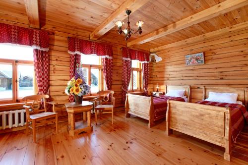 a bedroom in a log cabin with two beds and a table at Pushkarskaya Sloboda in Suzdal