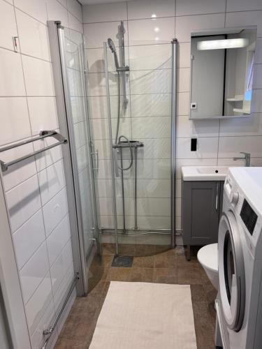 a bathroom with a shower and a washing machine at Mysig lägenhet med morgondopp in Uppsala
