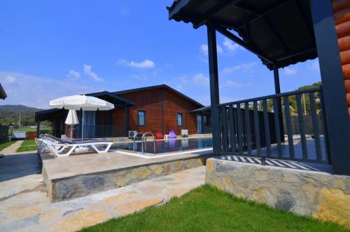 a patio with a bench and an umbrella and a house at Summertime Bungalows in Fethiye