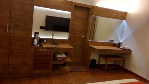 a room with a television and a desk with a mirror at Hotel Aravali in Mount Ābu