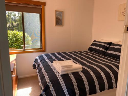a bedroom with a black and white bed and a window at Stewarts Bay Retreat in Port Arthur