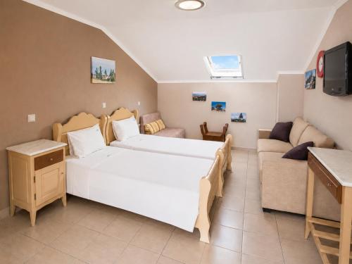 a hotel room with two beds and a couch at Hotel Dionysos Polichrono in Polychrono