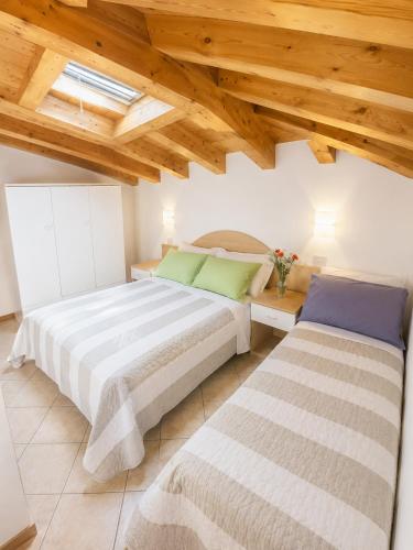 two beds in a room with wooden ceilings at Residence Guardamar - Agenzia Cocal in Caorle