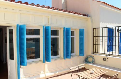 a house with blue shutters on a balcony at Chic Magnificent Sea View Suite in Andros
