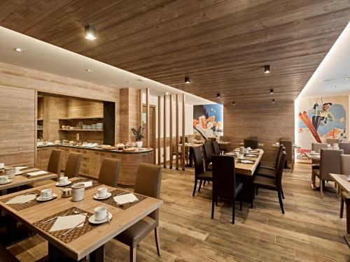 restauracja z drewnianymi podłogami, stołami i krzesłami w obiekcie Hotel Garni Arnica ***S w Madonna di Campiglio