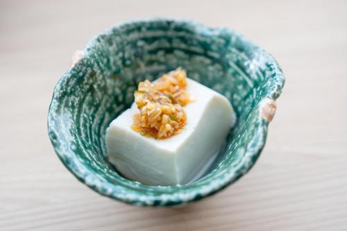 a green bowl with a piece of food in it at たびのホテル佐渡Annex in Sado