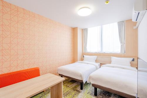 a room with two beds and a table at たびのホテル佐渡Annex in Sado
