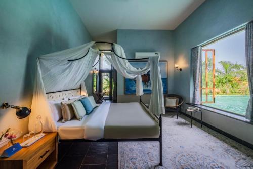 a bedroom with a canopy bed and a large window at SaffronStays Citadel in Sangolda