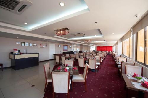 uma sala de jantar com mesas e cadeiras e um bar em Gaya Centre Hotel em Kota Kinabalu