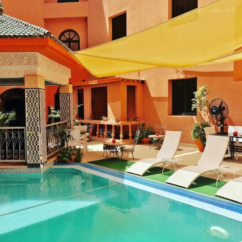 a swimming pool with white chairs and a yellow umbrella at Hotel tafoukt in Marrakesh
