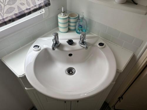 a white bathroom sink with two faucets on it at 11 Oaklands in Porchfield