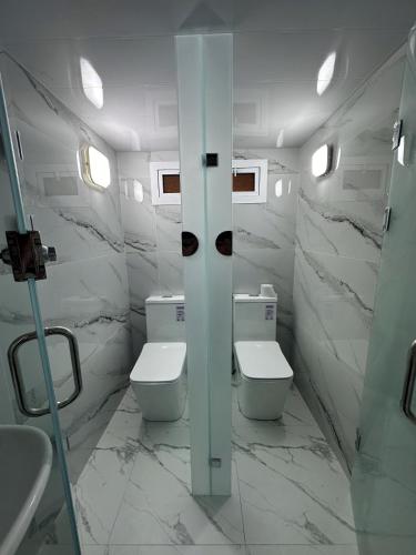 a white bathroom with two toilets and a sink at Aslan Hostel in Samarkand