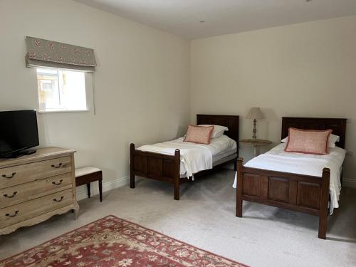 a bedroom with two beds and a tv and a dresser at Owl Barn in King's Lynn
