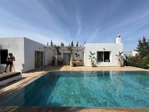 a woman walking by a swimming pool in a house at Villa TerraVerde in Al Ghar