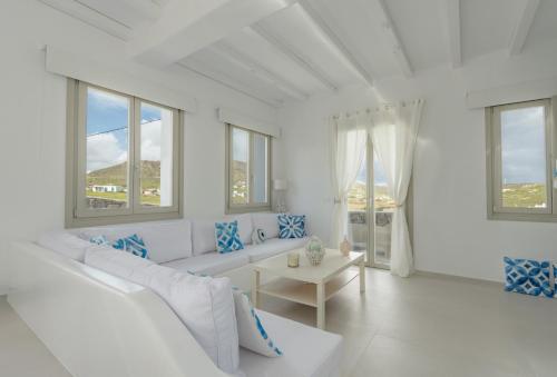 a white living room with a white couch and windows at Eidolion Essence - Mykonos Villa with Private Pool in Ano Mera
