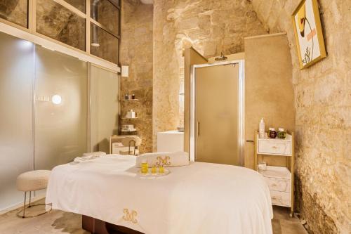 a bedroom with a white bed and a bathroom at La Maison d'Uzès Relais & Châteaux in Uzès