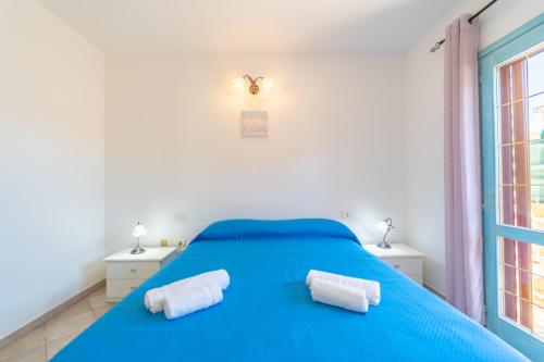 a bedroom with a blue bed with towels on it at Raffy by DomusAway in Porto San Paolo