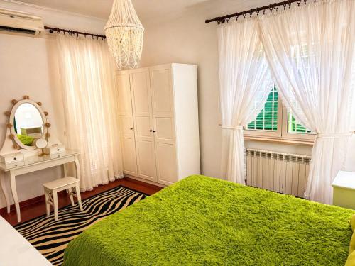 a bedroom with a green bed and a window at Villa SOLE di AMORE - POOL PRIVATE LARGE 100 M 2 - Beach 950m -Center 500 m - ROME & AIRPORT 39 km in Anzio