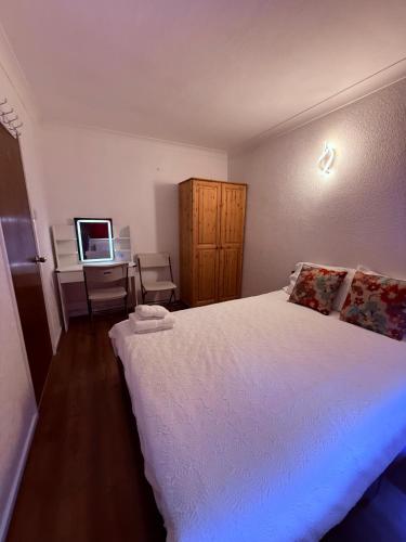 a bedroom with a white bed and a television at Andover Bungalow in Penton Mewsey