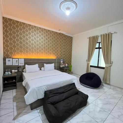 a large bedroom with a large bed and a chair at Hotel Grand Ansara Mentari in Baturaja
