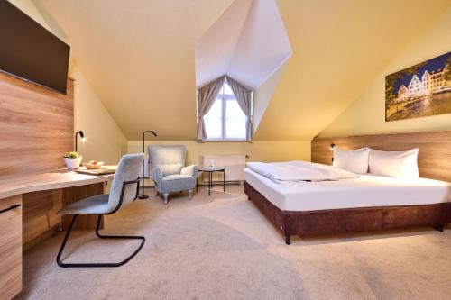 a bedroom with a bed and a desk and a chair at Hotel Linderhof in Erfurt