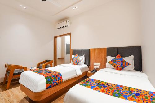 a hotel room with two beds and a chair at FabHotel A Square - 400m from Bhimavaram Junction in Bhīmavaram