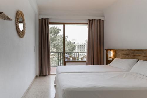 a bedroom with a bed and a large window at Hostal Palmaria in Cala Santanyi