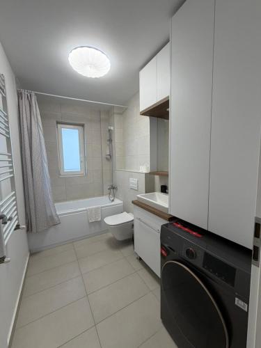 a white bathroom with a sink and a washing machine at Elite Noua in Braşov