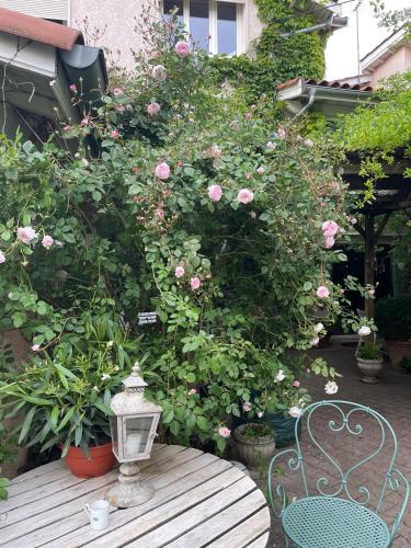 a wooden table with a lamp and pink roses at La rosée in Montanay