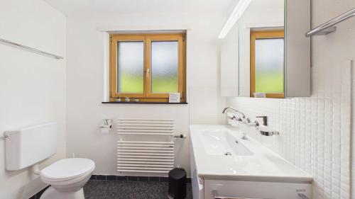a white bathroom with a toilet and a sink at Casa Terza - CharmingStay in Flumserberg