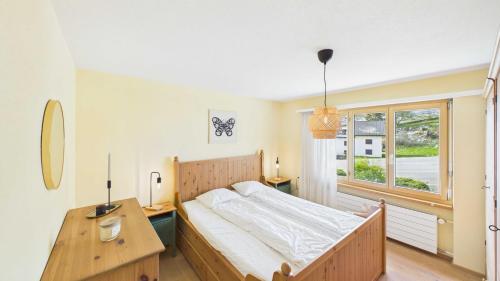 a bedroom with a bed and a desk and a window at Casa Terza - CharmingStay in Flumserberg