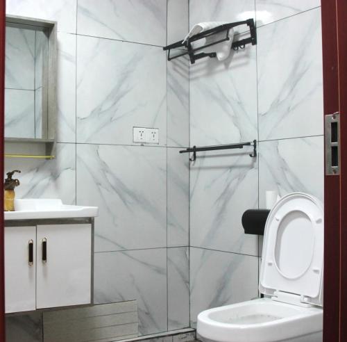a white bathroom with a toilet and a sink at Hotel Nana in Abidjan