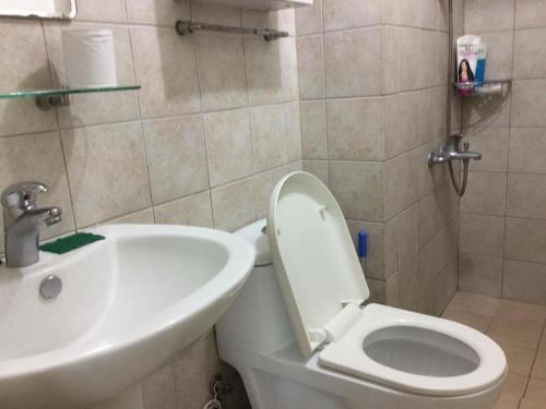 a bathroom with a white toilet and a sink at ORTIGAS 2 Br Corner Unit With 2 Queen Across Shangrila in Manila
