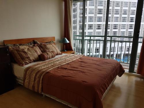 a bedroom with a bed and a large window at ORTIGAS 2 Br Corner Unit With 2 Queen Across Shangrila in Manila